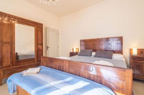 a bedroom with a large wooden bed and a mirror at Appartamento Poggio del Sole in Lucca