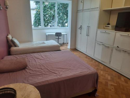 a room with two beds and a kitchen with a tv at Apto 5 quartos na Orla de Copacabana in Rio de Janeiro
