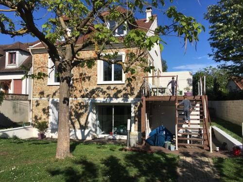 een man op het dek van een huis bij Studio au calme dans jardin à 30min de Paris avec NOUVELLE LITERIE in Chatou