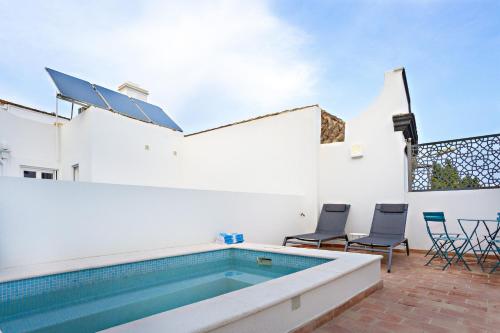 a swimming pool in a house with two chairs and a table at Amarela 17 in Tavira