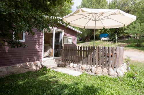a house with an umbrella and a fence at Camping Alta Ribagorça in El Pont de Suert