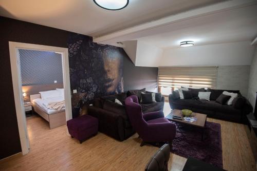 a living room with a couch and a bed at Hotel MUJEN LUX Wellness & Spa in Kopaonik
