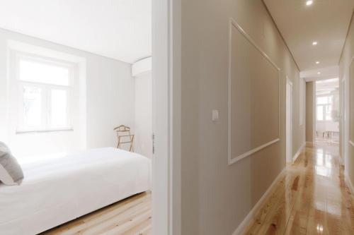 a white bedroom with a bed and a window at Apartamento Andrade in Lisbon