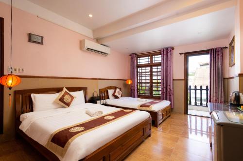 a hotel room with two beds and a window at Hoa My II Hotel in Hoi An