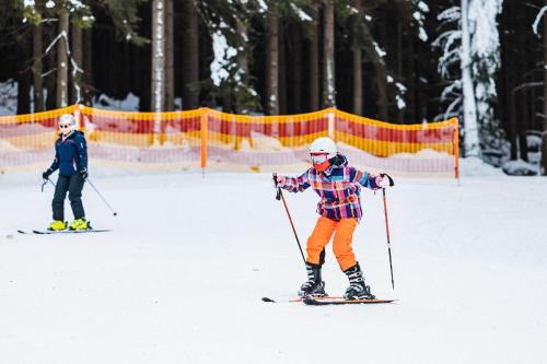 two people are skiing in the snow at Kazalnica Family&Conference Resort in Karpacz