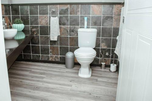a bathroom with a toilet and a tiled wall at Private luxurious 3 bedroom complete house in Bloemfontein