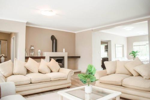 a living room with two white couches and a fireplace at Private luxurious 3 bedroom complete house in Bloemfontein