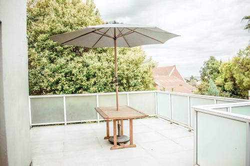 a wooden table with an umbrella on a balcony at Private luxurious 3 bedroom complete house in Bloemfontein