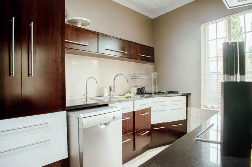 a kitchen with brown cabinets and white appliances at Private luxurious 3 bedroom complete house in Bloemfontein