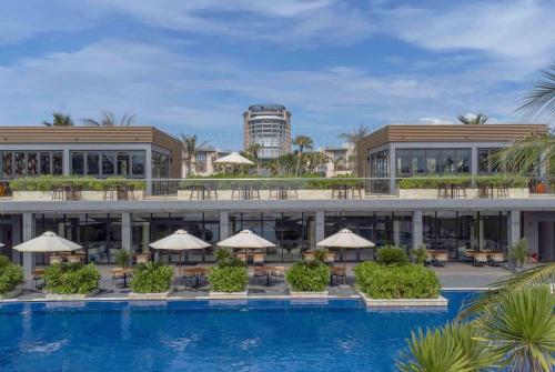 a resort with a swimming pool with tables and umbrellas at Wyndham Garden Cam Ranh Resort in Cam Ranh