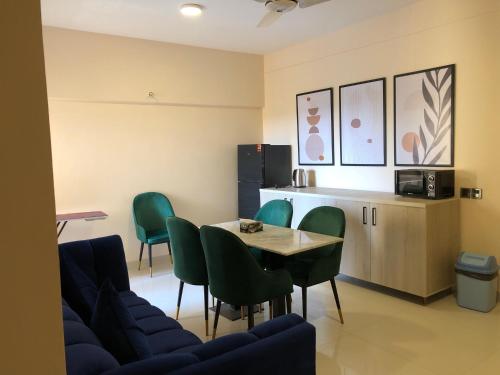 a waiting room with a table and green chairs at Hamsun Apart Hotel Clifton in Karachi