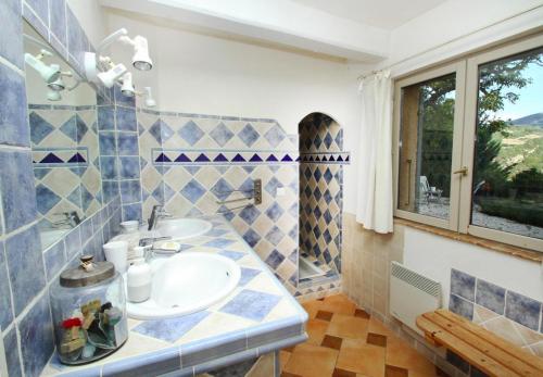 La salle de bains bleue et blanche est pourvue d'un lavabo et d'une fenêtre. dans l'établissement Le miau, à Vercoiran