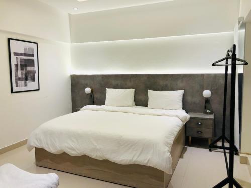 a bedroom with a large bed with white sheets at Hamsun Apart Hotel Clifton in Karachi