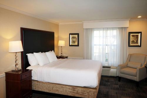 a hotel room with a bed and a chair at Wingate by Wyndham Bellingham Heritage Inn in Bellingham