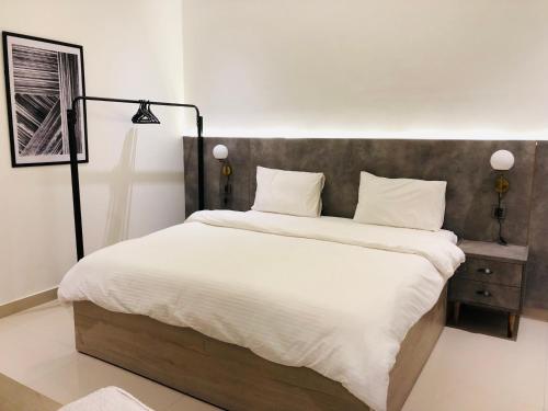a bedroom with a large bed with white sheets at Hamsun Apart Hotel Clifton in Karachi