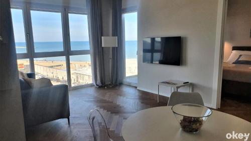 Sala de estar con mesa y vistas al océano en Seven Seas Luxury Apartments - Bari San Girolamo, en Bari