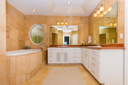 a bathroom with white cabinets and a tub and a sink at Lawson Rock - Angelfish 101 condo in Roatán