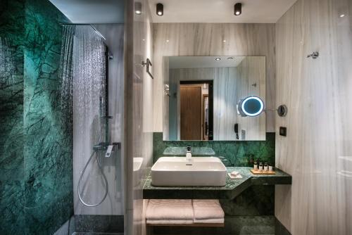 ein Bad mit einem Waschbecken, einer Dusche und einem Spiegel in der Unterkunft Dimargio Luxury Hotel & Spa in Iraklio