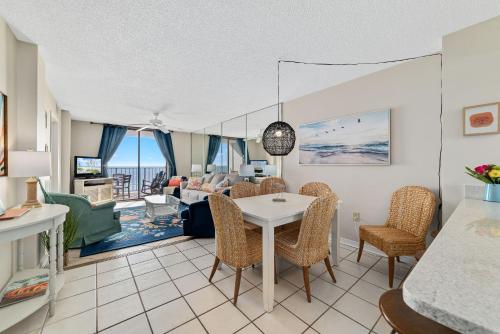 a dining room and living room with a table and chairs at Sunswept 702 condo in Orange Beach