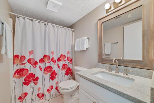 uma casa de banho com um WC e uma cortina de chuveiro com flores vermelhas em Sunswept 702 condo em Orange Beach