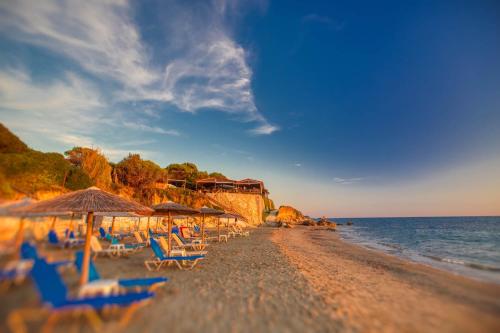 a beach with chairs and umbrellas and the ocean at Christinas apartments in Ágios Matthaíos