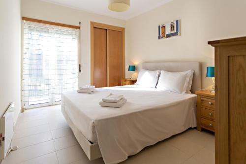 a bedroom with a large white bed with towels on it at Ocean Breeze Apartment in Cabanas de Tavira
