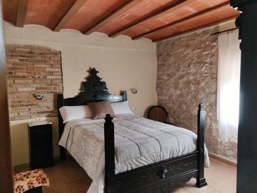 1 dormitorio con cama y pared de ladrillo en Casa Rural Espasa en Espluga de Francolí