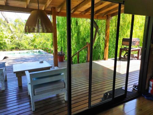 a porch with a bench and a table and a pool at Eco Cabaña Río - Cabaña Mirador in Tigre