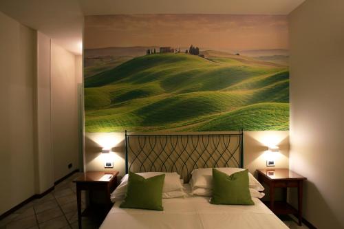 a bedroom with a bed with a painting on the wall at Hotel Le Colline in San Gimignano