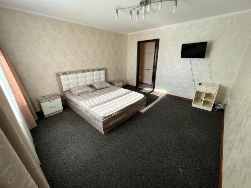 a bedroom with a bed and a tv in it at Бухар Жырау 76 in Karagandy
