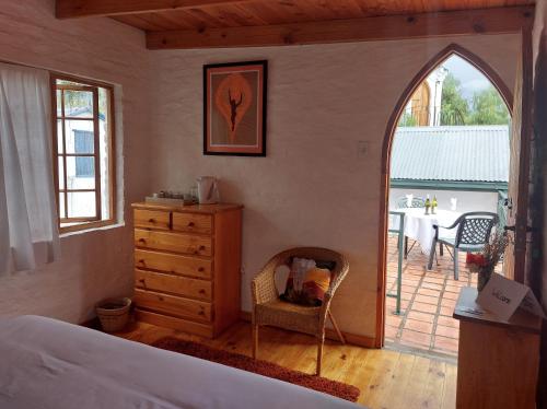 a bedroom with a bed and a dresser and a patio at Bethesda Tower Accommodation in Nieu-Bethesda