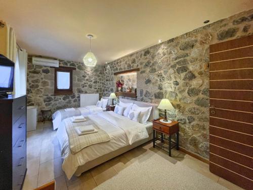 ein Schlafzimmer mit einem großen Bett und einer Steinmauer in der Unterkunft Ocazzia of Parnassos in Polydrosos