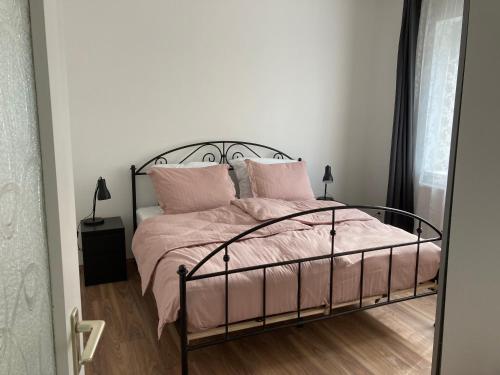 ein Schlafzimmer mit einem Bett mit rosa Decken und Kissen in der Unterkunft NAGYGÓLYA Appartementen in Szentistván