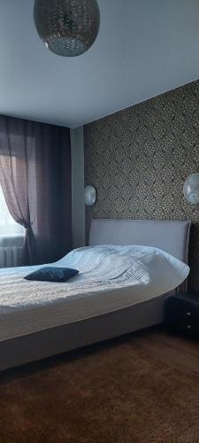 a bedroom with a bed with a white bedspread and a window at герасимова 12 in Narva