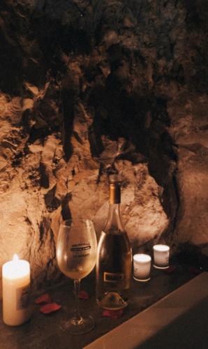 a bottle of wine and a glass next to candles at Gaiamoment,com - Cueva las reinas in Alcalá del Júcar