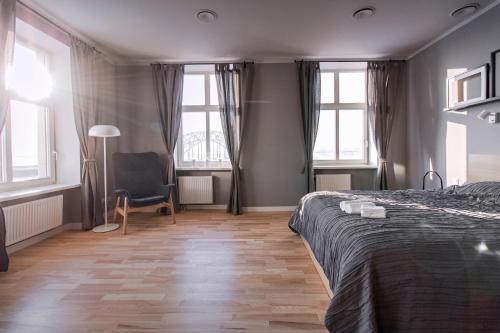 Modern apartment in Old Riga with a river view في ريغا: غرفة نوم بها سرير وكرسي ونوافذ
