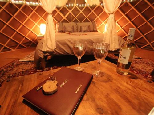 a table with a bottle of wine and two glasses at The Warren Yurt in Withyham