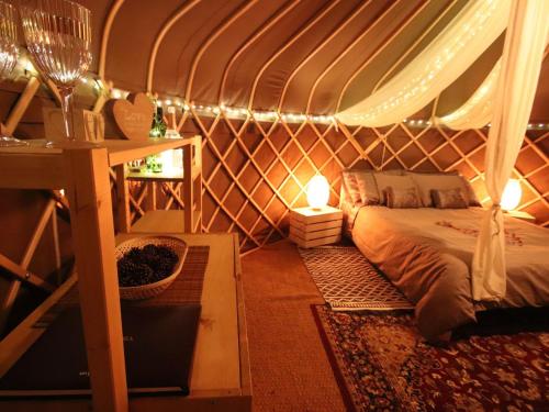 a room with a bed in a tent with lights at The Warren Yurt in Withyham