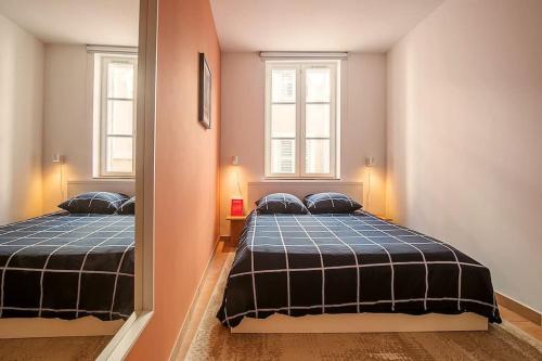 a bedroom with two beds and a mirror at Rare Appart 2 chambres en duplex design au Panier in Marseille