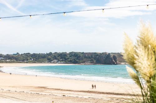 a beach with people walking on the sand and the ocean at St Brelade's Bay Hotel in St Brelade