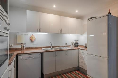 eine Küche mit weißen Schränken und einem weißen Kühlschrank in der Unterkunft Casa Das Videiras in Seixal