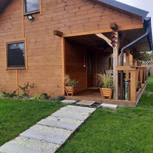 a wooden house with a patio with potted plants at Domek Na Roztoczu in Tomaszów Lubelski