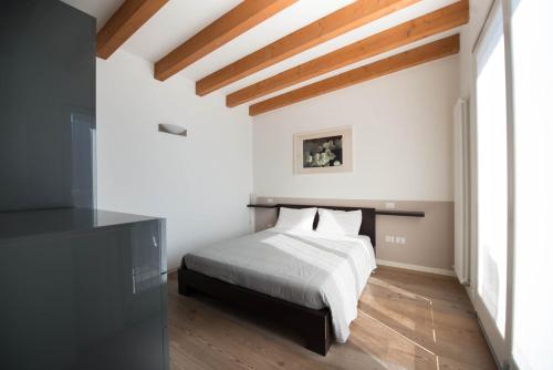 a bedroom with a white bed and wooden floors at Bertoldi Terme sul Garda - Terrazza in Nago-Torbole