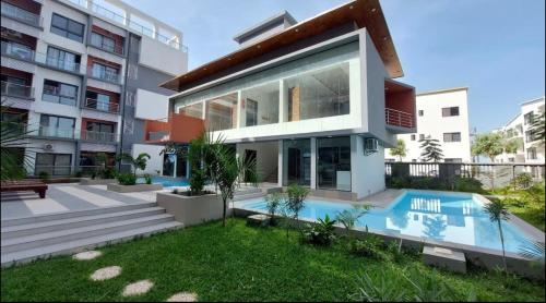 a house with a swimming pool in front of a building at Aminah’s Space - Jobz Luxury Rental in Bijilo