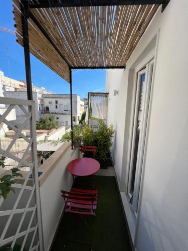 un pequeño balcón con mesa y sillas rojas en beddhra mia, en Lecce