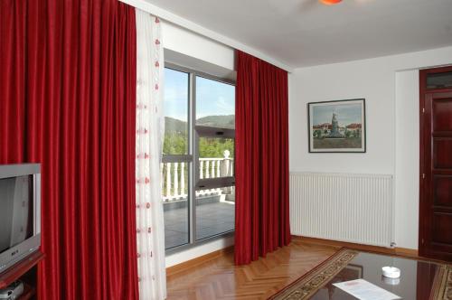 a living room with red curtains and a large window at Vila Lux Milikic in Kraljevo
