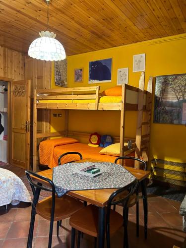 a room with two bunk beds and a table and chairs at B&B Il Nido in Riolunato