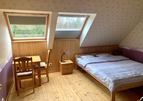 a bedroom with a bed and a desk and two windows at Holiday Home Veskijõe in Vaisi