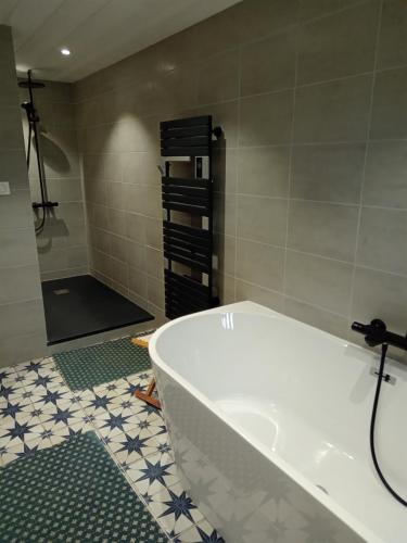 a white tub in a bathroom with a shower at Le 28 in Uzerche