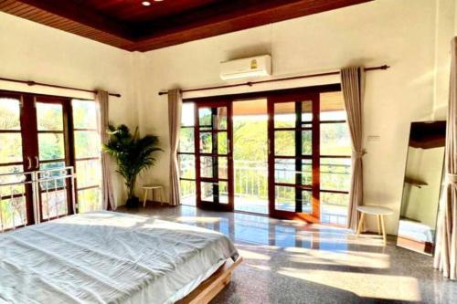 Schlafzimmer mit einem Bett und Glasschiebetüren in der Unterkunft Lake & lotus ponds view 2nd floor Villa in Thongsala